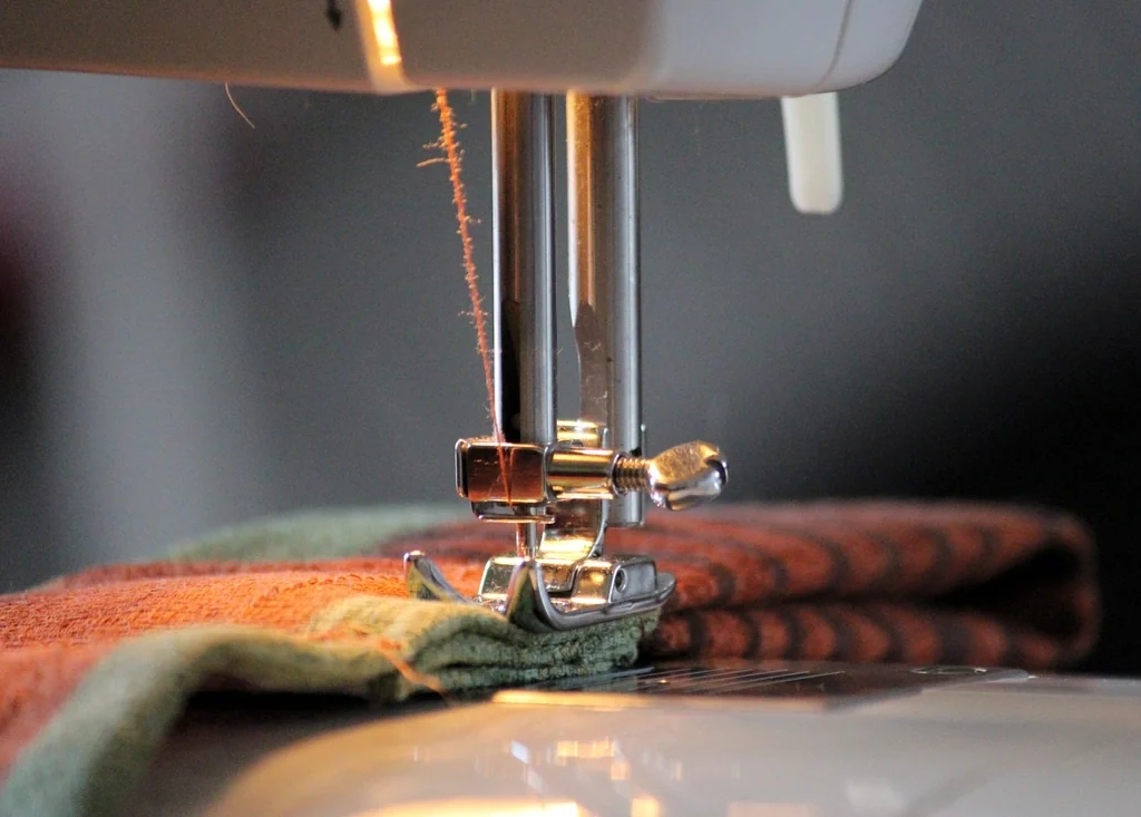 A sewing machine foot stitching the edge of a folded towel